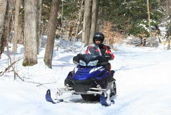 Snowmobiler on a snowmobile trail in the woods